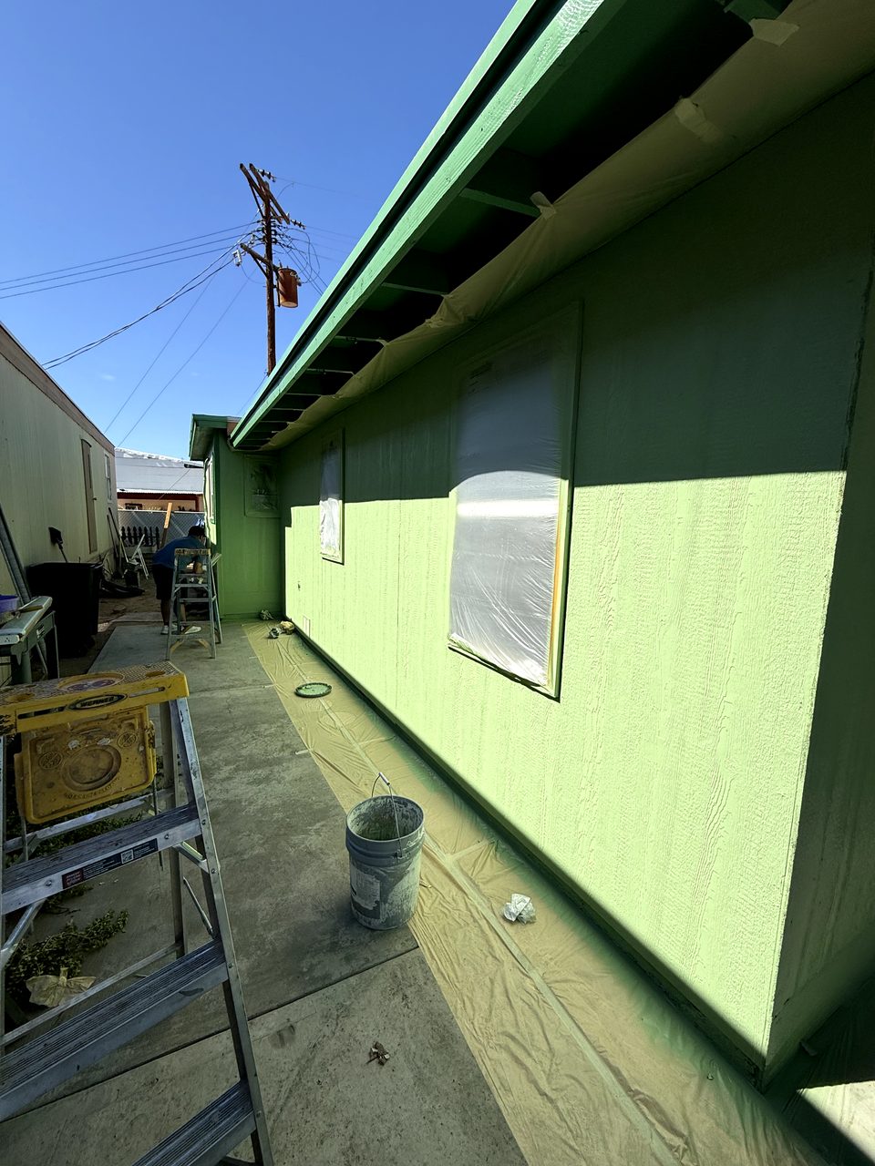 Ventanas cubiertas con plástico y lonas en el piso durante el repintado de lámina en Phoenix
