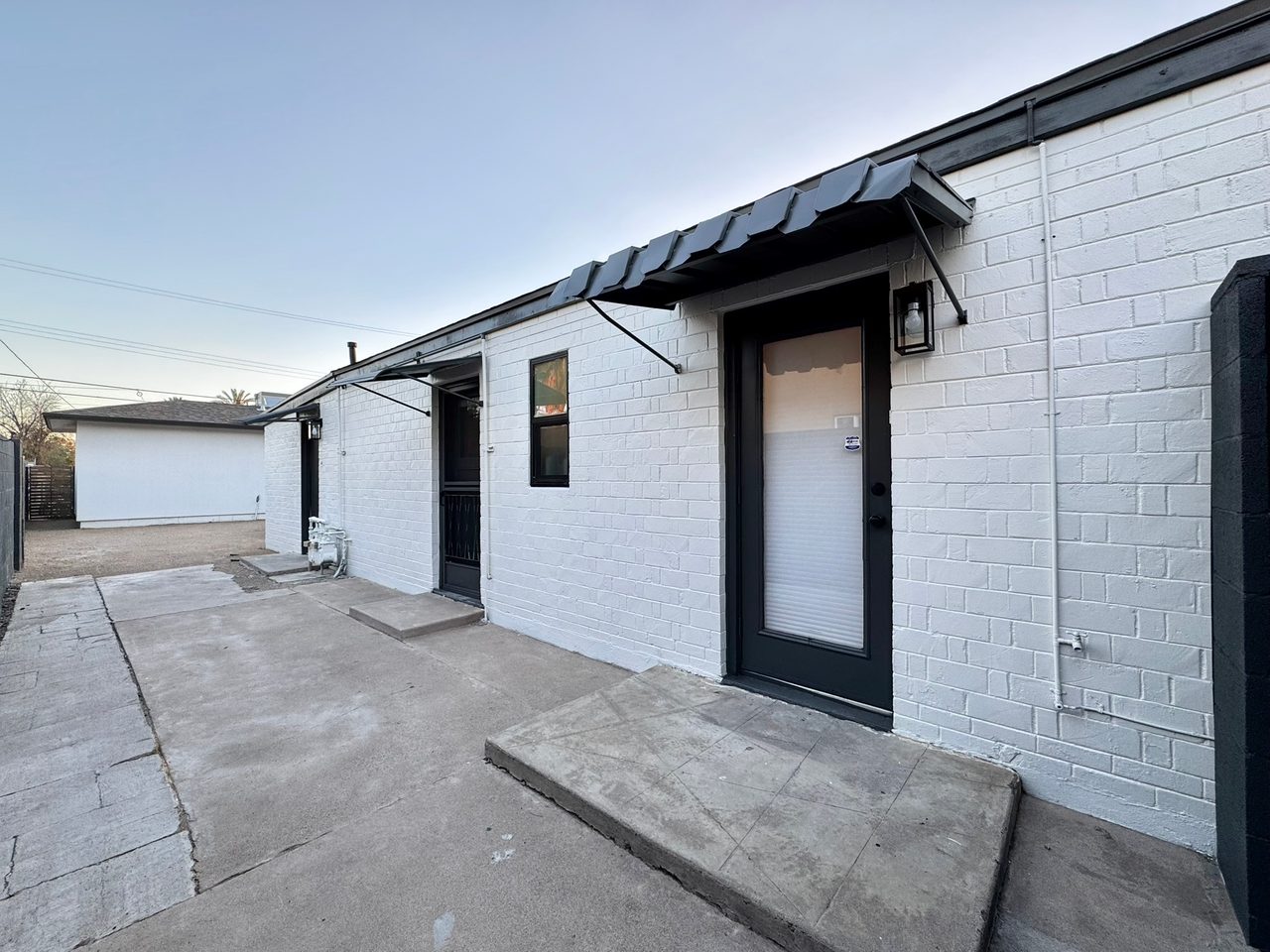 Finished side entry with crisp white brick, black door, and a black metal awning
